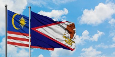 Malezya ve Amerikan Samoası bayrağı birlikte beyaz bulutlu mavi gökyüzüne karşı rüzgarda sallayarak. Diplomasi kavramı, uluslararası ilişkiler.