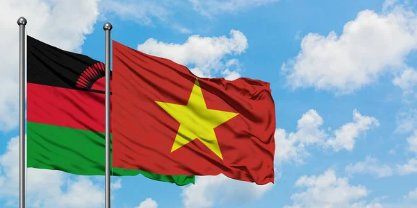 Bandera de Malawi y Vietnam ondeando en el viento contra el cielo azul nublado blanco juntos. Concepto diplomático, relaciones internacionales . — Foto de Stock