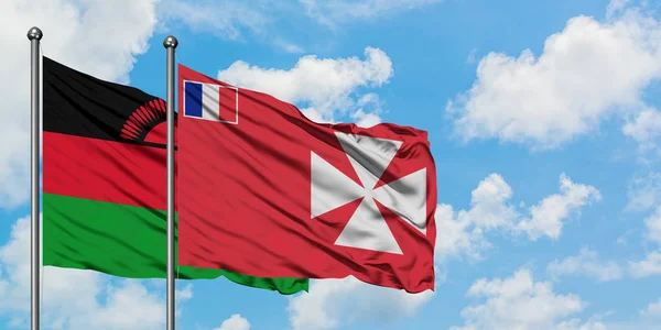 Malawi y Wallis y la bandera de Futuna ondeando en el viento contra el cielo azul nublado blanco juntos. Concepto diplomático, relaciones internacionales . — Foto de Stock