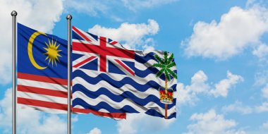 Malezya ve İngiliz Hint Okyanusu Toprakları bayrağı birlikte beyaz bulutlu mavi gökyüzüne karşı rüzgarda sallayarak. Diplomasi kavramı, uluslararası ilişkiler.