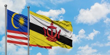 Malezya ve Brunei bayrağı birlikte beyaz bulutlu mavi gökyüzüne karşı rüzgarda sallayarak. Diplomasi kavramı, uluslararası ilişkiler.