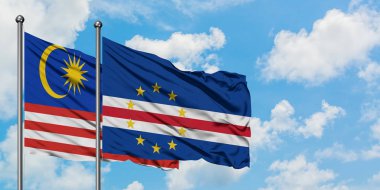 Malezya ve Cape Verde bayrağı birlikte beyaz bulutlu mavi gökyüzüne karşı rüzgarda sallayarak. Diplomasi kavramı, uluslararası ilişkiler.
