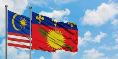 Malezya ve Guadeloupe bayrağı birlikte beyaz bulutlu mavi gökyüzüne karşı rüzgarda sallayarak. Diplomasi kavramı, uluslararası ilişkiler.