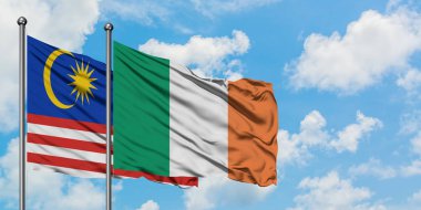 Malezya ve İrlanda bayrağı birlikte beyaz bulutlu mavi gökyüzüne karşı rüzgarda sallayarak. Diplomasi kavramı, uluslararası ilişkiler.