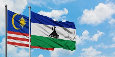 Malezya ve Lesotho bayrağı birlikte beyaz bulutlu mavi gökyüzüne karşı rüzgarda sallayarak. Diplomasi kavramı, uluslararası ilişkiler.