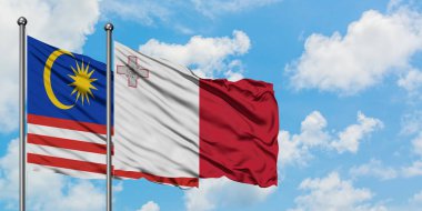 Malezya ve Malta bayrağı birlikte beyaz bulutlu mavi gökyüzüne karşı rüzgarda sallayarak. Diplomasi kavramı, uluslararası ilişkiler.