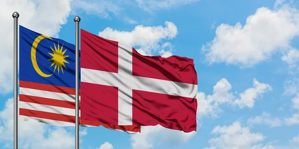一緒に白い曇った青い空に対して風に手を振るマレーシアとデンマークの旗。外交概念、国際関係. — ストック写真