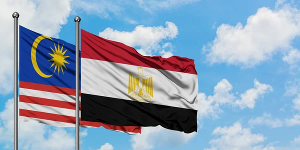 Bandera de Malasia y Egipto ondeando en el viento contra el cielo azul nublado blanco juntos. Concepto diplomático, relaciones internacionales . — Foto de Stock