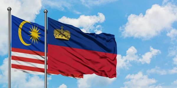 Malezya ve Lihtenştayn bayrağı birlikte beyaz bulutlu mavi gökyüzüne karşı rüzgarda sallayarak. Diplomasi kavramı, uluslararası ilişkiler. — Stok fotoğraf