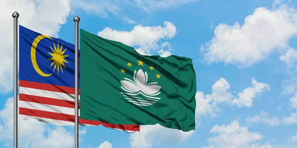 Malaysia and Macao flag waving in the wind against white cloudy blue sky together. Diplomacy concept, international relations.
