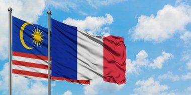 Malezya ve Reunion bayrağı birlikte beyaz bulutlu mavi gökyüzüne karşı rüzgarda sallayarak. Diplomasi kavramı, uluslararası ilişkiler.