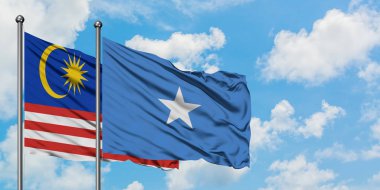 Malezya ve Somali bayrağı birlikte beyaz bulutlu mavi gökyüzüne karşı rüzgarsal sallayarak. Diplomasi kavramı, uluslararası ilişkiler.