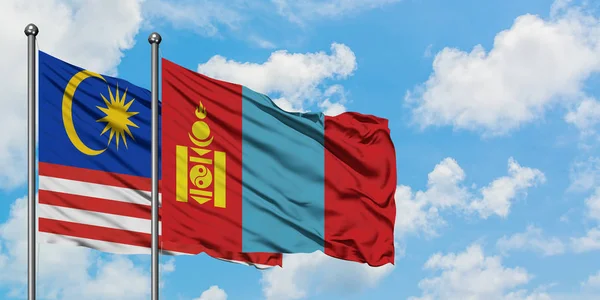 Gemeinsam wehen malaysische und mongolische Flaggen im Wind gegen den wolkenverhangenen blauen Himmel. Diplomatie-Konzept, internationale Beziehungen. — Stockfoto