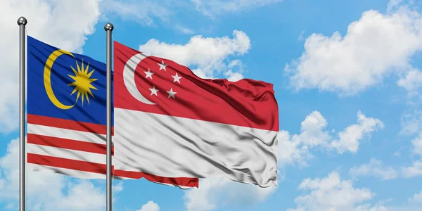 马来西亚和新加坡国旗在风中飘扬，与白云蓝天相一起。外交概念、国际关系. — 图库照片