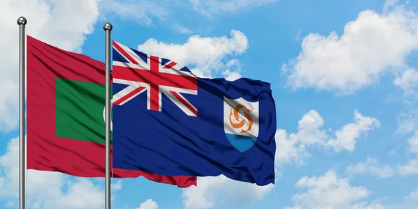 Maldivas y bandera de Anguila ondeando en el viento contra el cielo azul nublado blanco juntos. Concepto diplomático, relaciones internacionales . — Foto de Stock