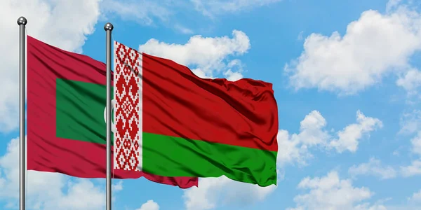 Maldivas y bandera de Bielorrusia ondeando en el viento contra el cielo azul nublado blanco juntas. Concepto diplomático, relaciones internacionales . — Foto de Stock
