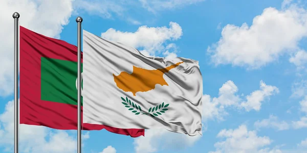 Maldivas y la bandera de Chipre ondeando en el viento contra el cielo azul nublado blanco juntos. Concepto diplomático, relaciones internacionales . — Foto de Stock