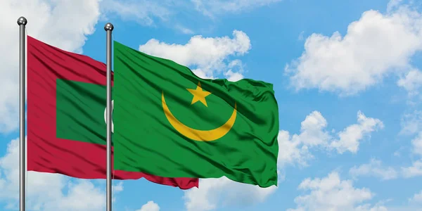 Bandera de Maldivas y Mauritania ondeando en el viento contra el cielo azul nublado blanco juntos. Concepto diplomático, relaciones internacionales . — Foto de Stock