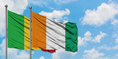 Mali ve Fildişi Sahili bayrağı birlikte beyaz bulutlu mavi gökyüzüne karşı rüzgarda sallayarak. Diplomasi kavramı, uluslararası ilişkiler.