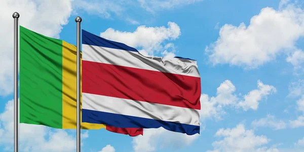 Bandera de Malí y Costa Rica ondeando en el viento contra el cielo azul nublado blanco juntos. Concepto diplomático, relaciones internacionales . — Foto de Stock