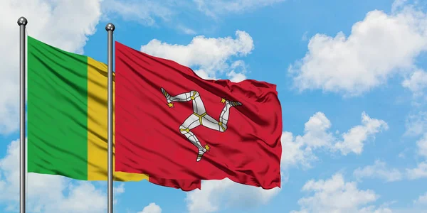 Malí y la bandera de la Isla de Man ondeando en el viento contra el cielo azul nublado blanco juntos. Concepto diplomático, relaciones internacionales . — Foto de Stock