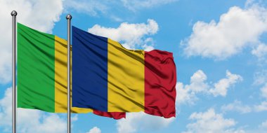 Mali ve Romanya bayrağı birlikte beyaz bulutlu mavi gökyüzüne karşı rüzgarda sallayarak. Diplomasi kavramı, uluslararası ilişkiler.