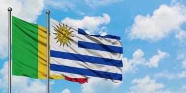 Mali ve Uruguay bayrağı birlikte beyaz bulutlu mavi gökyüzüne karşı rüzgarsal sallayarak. Diplomasi kavramı, uluslararası ilişkiler.