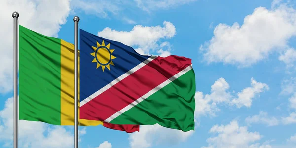 Bandera de Malí y Namibia ondeando en el viento contra el cielo azul nublado blanco juntos. Concepto diplomático, relaciones internacionales . — Foto de Stock