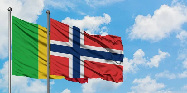 Bandera de Malí y Noruega ondeando en el viento contra el cielo azul nublado blanco juntos. Concepto diplomático, relaciones internacionales . — Foto de Stock