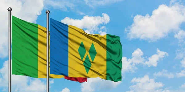 Le Mali et Saint-Vincent-et-les Grenadines agitent ensemble leur drapeau dans le vent contre un ciel bleu nuageux blanc. Concept de diplomatie, relations internationales . — Photo