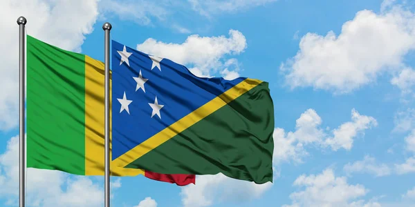 Bandera de Malí y las Islas Salomón ondeando en el viento contra el cielo azul nublado blanco juntos. Concepto diplomático, relaciones internacionales . — Foto de Stock