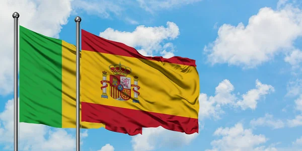 Bandera de Malí y España ondeando en el viento contra el cielo azul nublado blanco juntos. Concepto diplomático, relaciones internacionales . — Foto de Stock