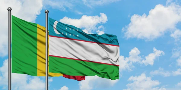 Bandera de Malí y Uzbekistán ondeando en el viento contra el cielo azul nublado blanco juntos. Concepto diplomático, relaciones internacionales . — Foto de Stock