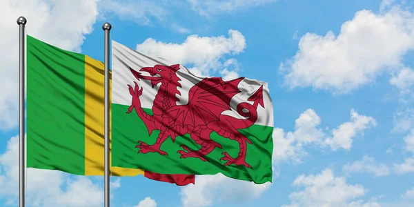 Bandeira do Mali e do País de Gales agitando no vento contra o céu azul nublado branco juntos. Conceito de diplomacia, relações internacionais . — Fotografia de Stock