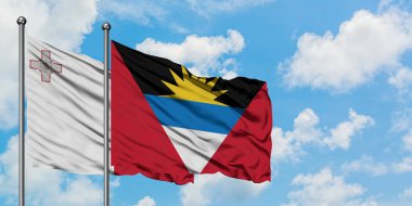 Malta ve Antigua ve Barbuda bayrağı birlikte beyaz bulutlu mavi gökyüzüne karşı rüzgarda sallayarak. Diplomasi kavramı, uluslararası ilişkiler.