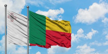 Malta ve Benin bayrağı birlikte beyaz bulutlu mavi gökyüzüne karşı rüzgarda sallayarak. Diplomasi kavramı, uluslararası ilişkiler.