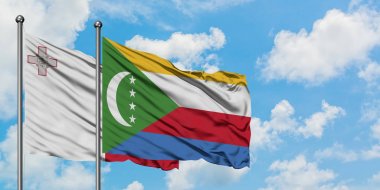 Malta ve Komorbayrağı birlikte beyaz bulutlu mavi gökyüzüne karşı rüzgarda sallayarak. Diplomasi kavramı, uluslararası ilişkiler.