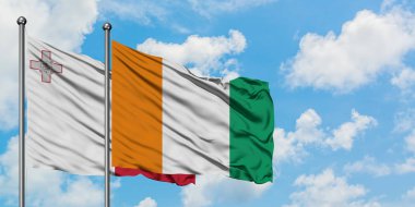 Malta ve Fildişi Sahili bayrağı birlikte beyaz bulutlu mavi gökyüzüne karşı rüzgarda sallayarak. Diplomasi kavramı, uluslararası ilişkiler.