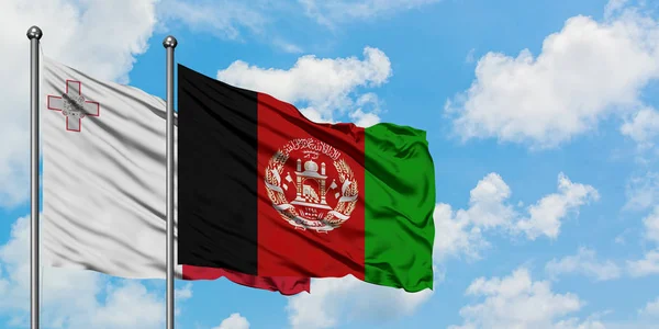 Bandera de Malta y Afganistán ondeando en el viento contra el cielo azul nublado blanco juntos. Concepto diplomático, relaciones internacionales . — Foto de Stock