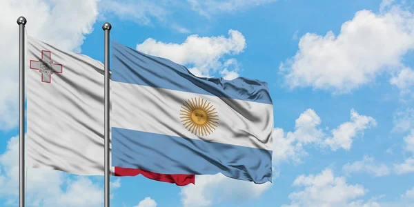 Bandera de Malta y Argentina ondeando en el viento contra el cielo azul nublado blanco juntos. Concepto diplomático, relaciones internacionales . — Foto de Stock
