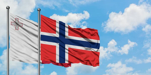 Bandera de Malta y Bouvet Islands ondeando en el viento contra el cielo azul nublado blanco juntos. Concepto diplomático, relaciones internacionales . —  Fotos de Stock