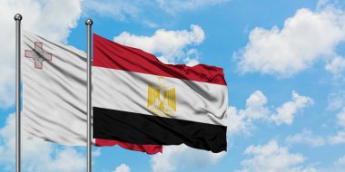 Malta ve Mısır bayrağı birlikte beyaz bulutlu mavi gökyüzüne karşı rüzgarda sallayarak. Diplomasi kavramı, uluslararası ilişkiler.
