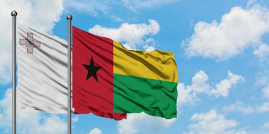 Malta ve Gine Bissau bayrağı birlikte beyaz bulutlu mavi gökyüzüne karşı rüzgarda sallayarak. Diplomasi kavramı, uluslararası ilişkiler.