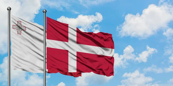 Malta och Danmark sjunker vifta i vinden mot vit grumlig blå himmel tillsammans. Diplomatisk koncept, internationella relationer. — Stockfoto