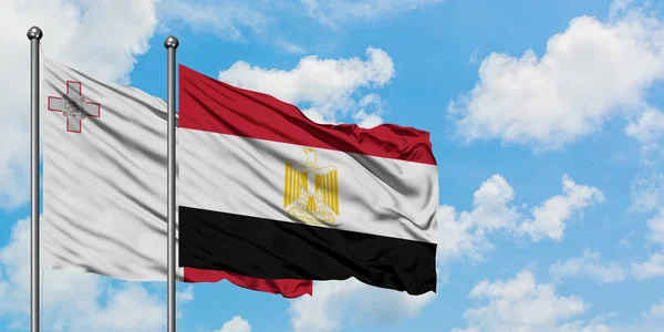 Bandera de Malta y Egipto ondeando en el viento contra el cielo azul nublado blanco juntos. Concepto diplomático, relaciones internacionales . — Foto de Stock