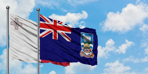 Malta och Falklandsöarnas flagga vifta i vinden mot vit grumlig blå himmel tillsammans. Diplomatisk koncept, internationella relationer. — Stockfoto