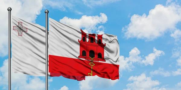 Malta e Gibraltar acenam ao vento contra o céu azul nublado branco juntos. Conceito de diplomacia, relações internacionais . — Fotografia de Stock