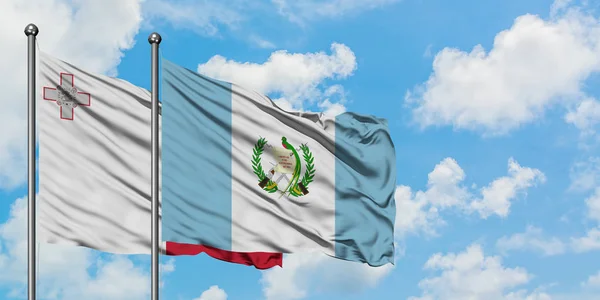 Malta und Guatemala schwenken gemeinsam die Flagge im Wind vor dem wolkenverhangenen blauen Himmel. Diplomatie-Konzept, internationale Beziehungen. — Stockfoto