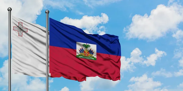 Malta en Haïti vlag zwaaien in de wind tegen witte bewolkte blauwe hemel samen. Diplomatie concept, internationale betrekkingen. — Stockfoto