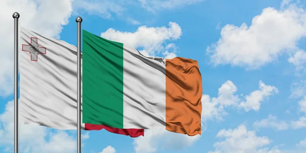 Malte et l'Irlande drapeau agitant dans le vent contre ciel bleu nuageux blanc ensemble. Concept de diplomatie, relations internationales . — Photo